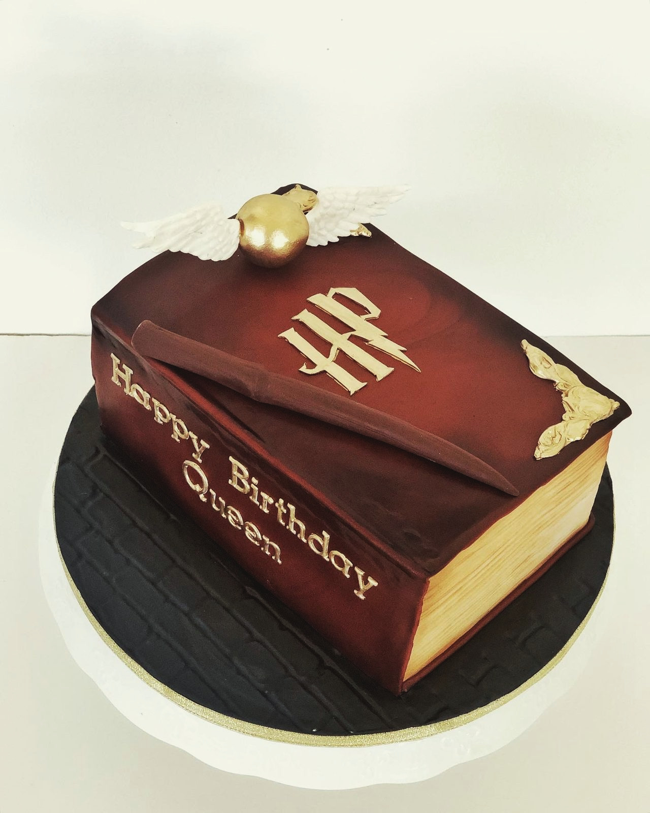 A leather-bound cake book with a winged golden snitch
