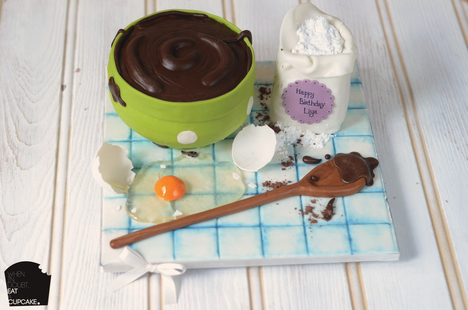 Chocolate batter in a green bowl with eggs and spoon, all cake
