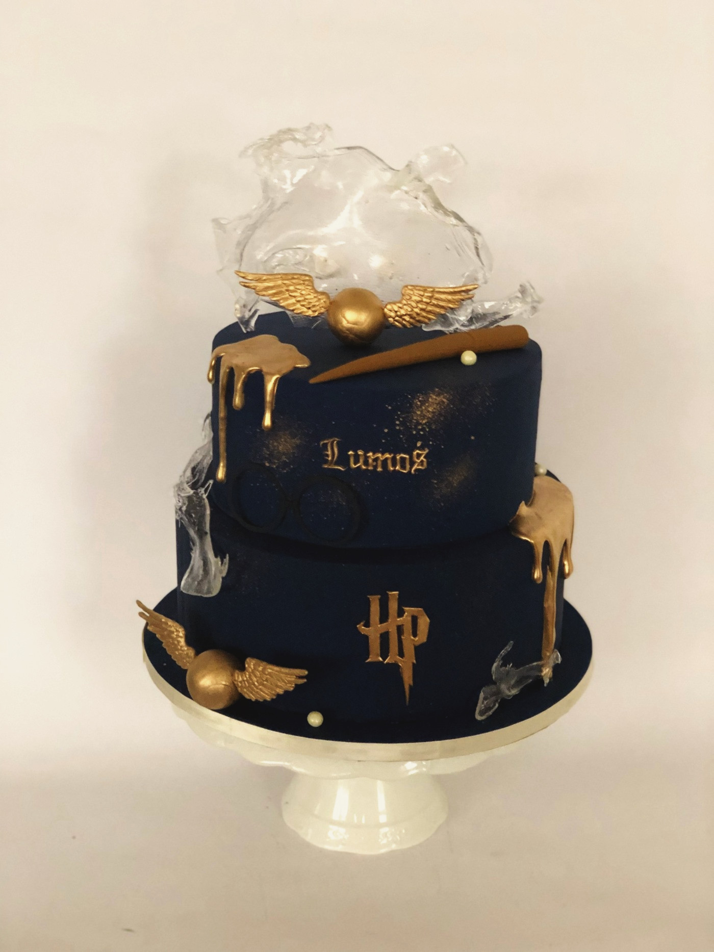 Navy Harry Potter cake with a gold snitch, glasses, wand and sugar-glass patronus