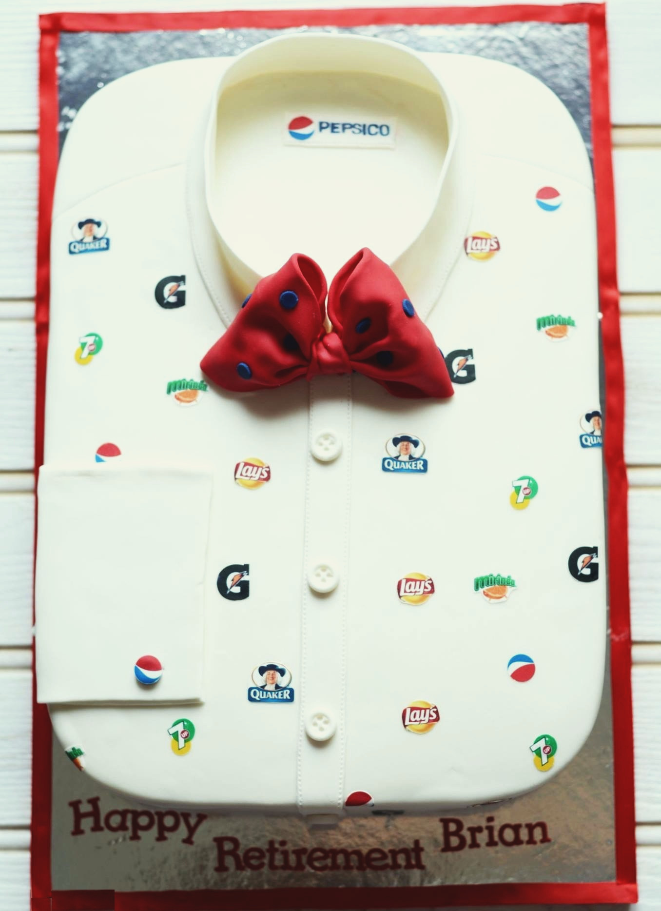 Shirt-shaped cake with a red polka-dot bow tie and PepsiCo brand logos