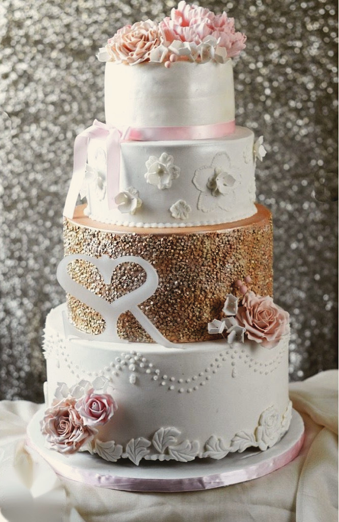 Four tier white and rose gold wedding cake with sugar roses and an acrylic monogram topper
